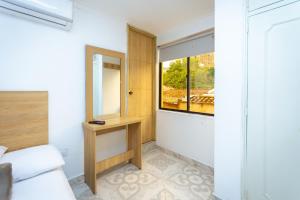 a bedroom with a window and a bed and a mirror at Hotel Colores Boutique in Medellín