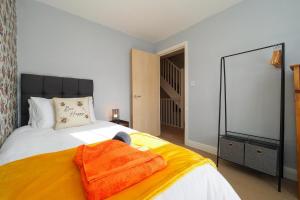 a bedroom with a bed with an orange blanket on it at Spacious Comfy 4 Bed Home - Sleeps up to 7 & Pets in Derby