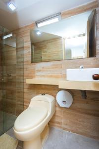 a bathroom with a toilet and a sink and a mirror at Hotel Colores Boutique in Medellín