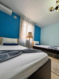 a bedroom with two beds and a blue wall at Luxe Home in Shkodër