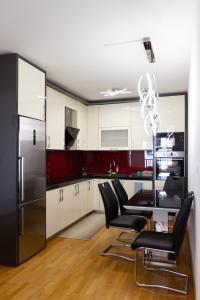 a kitchen with a black refrigerator and black chairs at Aylin Apartman in Sarajevo