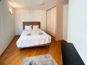 a bedroom with a bed with white sheets and wood floors at Aylin Apartman in Sarajevo