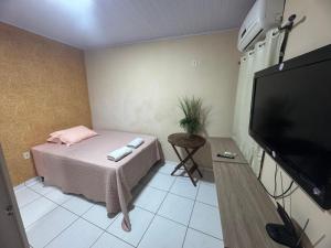 a room with a bed and a flat screen tv at Quarto em AP compartilhado Ponta da areia in São Luís