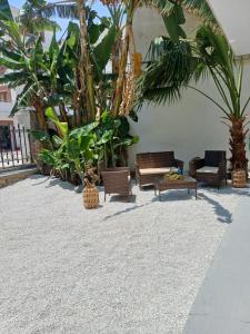a patio with chairs and tables and palm trees at Urban Garden Suite-Samos Center in Samos