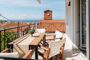 a balcony with a table and chairs and a clock tower at SIDI apartments in Polychrono