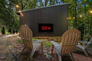 two chairs and a tv in front of a building at Couple's Cabin With Outdoor Movies, Firepit and Hot Tub - Rose Peak Loft in Blue Ridge