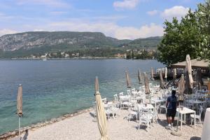 a group of tables and chairs on a beach with the water at Monika Holiday 619 Green Garda Lake in Garda