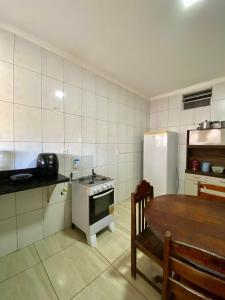 a kitchen with a table and a stove and a refrigerator at Casa Empório 15 in Lagoa Nova