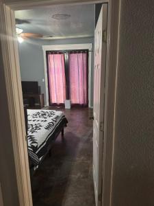 a bedroom with a bed and two windows with pink curtains at Master bedroom in Bakersfield