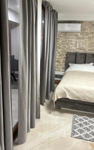 a bedroom with a bed and a stone wall at House Sela vrata in Bibinje