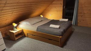 una camera da letto con un letto in una stanza di legno di Chata Wilka Bieszczady - Całoroczny dom z bali z 3 sypialniami i balią a Brzegi Dolne