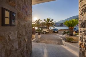 a building with a parking lot with palm trees at Adrian in Rafailovici