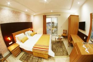 een hotelkamer met een bed en een televisie bij Hotel Julius in El Jem