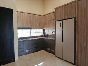 eine Küche mit Holzschränken und einem Kühlschrank in der Unterkunft Villa Tasnim Syariah Landungsari in 