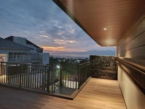 einen Balkon mit Blick auf die Stadt bei Sonnenuntergang in der Unterkunft Villa Tasnim Syariah Landungsari in 