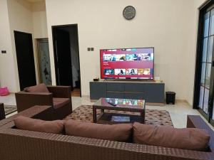 ein Wohnzimmer mit Couch und Flachbildfernseher in der Unterkunft Villa Tasnim Syariah Landungsari in 