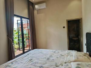 ein Schlafzimmer mit einem Bett und einem großen Fenster in der Unterkunft Villa Tasnim Syariah Landungsari in 