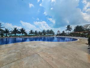a swimming pool at a resort with palm trees at Beachfront apartments Cancun in Cancún