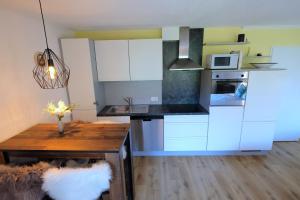 a kitchen with white cabinets and a wooden table at Charming Studio - Ferienwohnung - Vulpera, Scuol in Scuol
