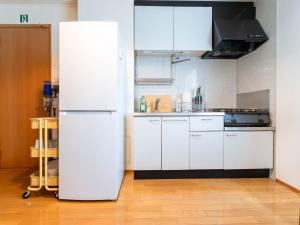 a white refrigerator in a kitchen with white cabinets at utasto azuki 2F in Utazu
