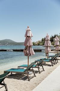 a row of lounge chairs and umbrellas on a beach at All'oro in Njivice