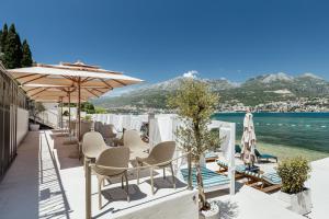 a patio with chairs and umbrellas and the ocean at All'oro in Njivice