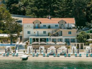 a hotel with chairs and umbrellas next to the water at All'oro in Njivice