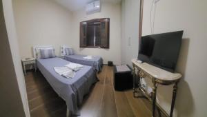 a room with two beds and a flat screen tv at LM Hotel Araçatuba in Araçatuba