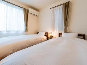 two white beds in a room with a window at utasto olive 1F in Utazu