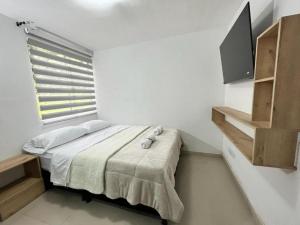a white bedroom with a bed and a window at Apartamento confortable y tranquilo in Manizales