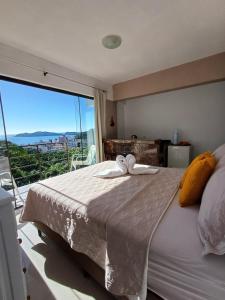 a bedroom with a large bed with a large window at Suíte com vista panorâmica in Bombinhas