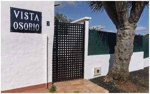 a white building with a black gate next to a tree at Vista Osorio in Teror