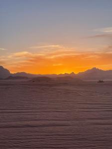 a sunset in the desert with mountains in the background at Moon Camp in Al Jafr