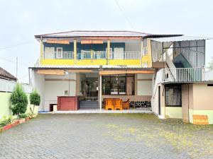 a house with a yellow and white at RedDoorz Syariah at Nusa Indah near BNS in Batu