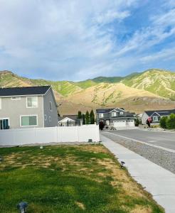 a house on a street with mountains in the background at Cozy Apartment Near Hiking Trails & SLC Airport in Lake Point