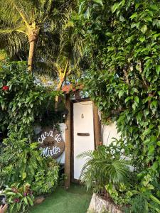 a white door with a sign in a garden at Casa de Mirtes in Fernando de Noronha