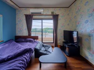 a bedroom with two beds and a tv and a chair at Kamogawa Sunset Villa - 鴨川サンセットヴィラ in Kamogawa