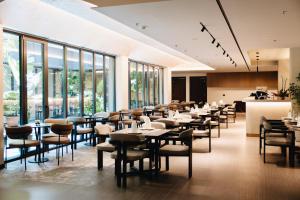 Un restaurante con mesas y sillas y grandes ventanales. en Grand Duka Hotel & SPA, en Durrës