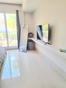 a white bedroom with a tv and a window at Condo Azul in Cancún +4 photos