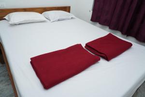 a white bed with two red towels on it at Garcinia Villa in Sirsi