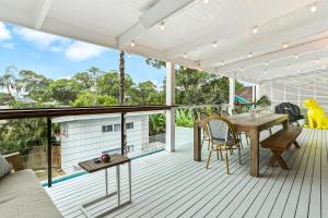 una terraza al aire libre con mesa de madera y sillas en Coastal Luxe Little Cove Noosa, en Noosa Heads