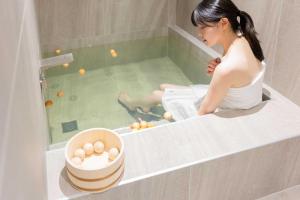 大田Aank Hotel and Spa Daejeon Yuseong的一位女士坐在浴缸里，手里拿着一碗鸡蛋