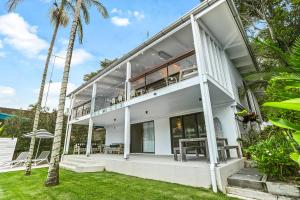 una casa blanca con palmeras en el patio en Coastal Luxe Little Cove Noosa, en Noosa Heads