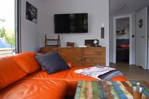 ein orangefarbenes Sofa im Wohnzimmer mit einem TV in der Unterkunft Houseboat Leni, Flensburg in Flensburg + 36 Fotos