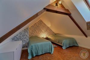 a attic room with two beds in the attic at Le fournil in Vezin-le-Coquet