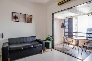 a living room with a black leather couch and a table at Flat c/ Limpeza Diária | Piscina e Praia - DL1804 in Recife