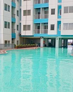 a large swimming pool in front of a building at Cozy 1BR Apartment with Home Office at The Nest Jakarta Barat in Jakarta