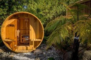 Una pequeña sauna de madera en un jardín con árboles. en Tasman Holiday Parks - Te Anau, en Te Anau