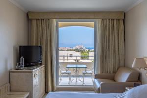 a hotel room with a bed and a view of a patio at Hotel Corsica & Spa Serena in Calvi
