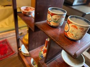 a shelf with three cups and bowls on it at はたご屋ちゅうべ in Taki